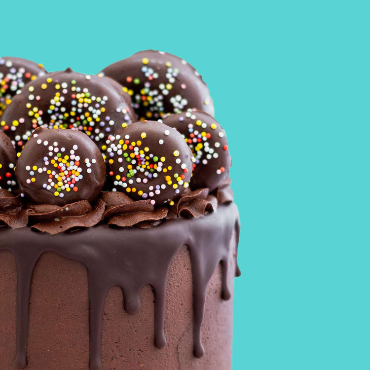 chocolate cake with mini donuts on top over teal background